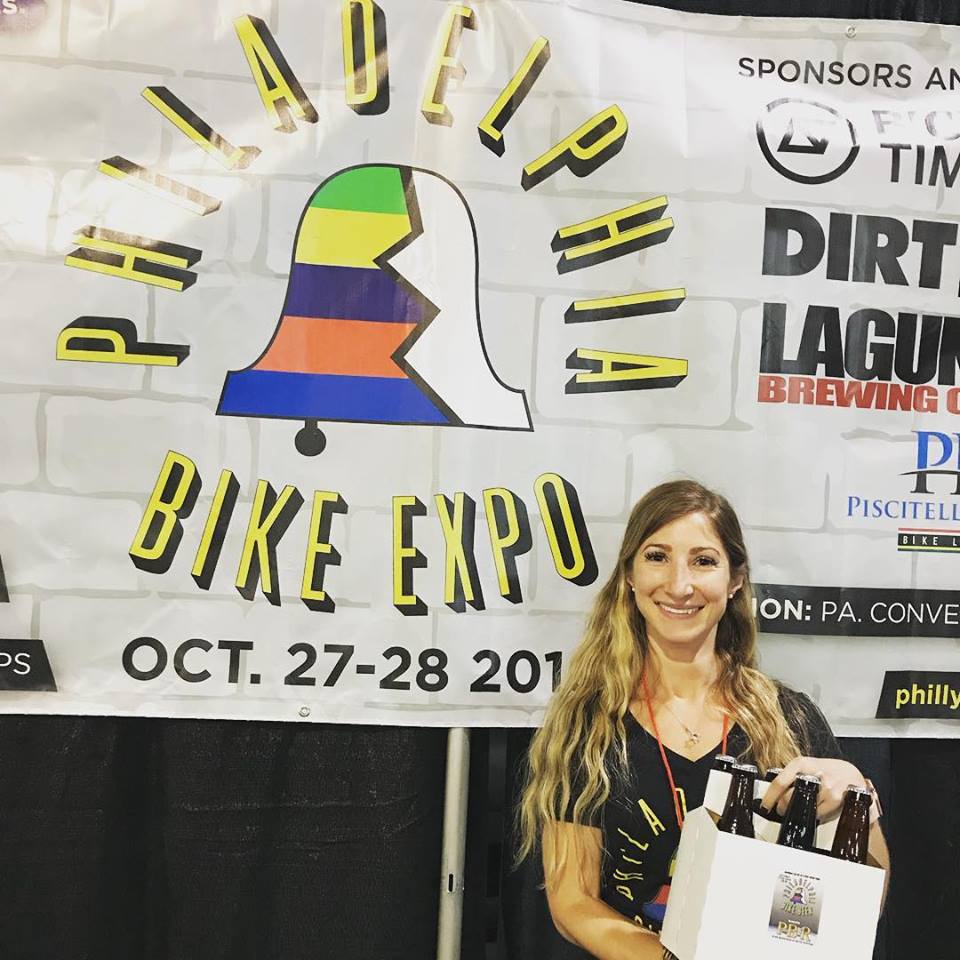 @phillybikeexpo director @binabilenky poses by Expo Sponsor signage.