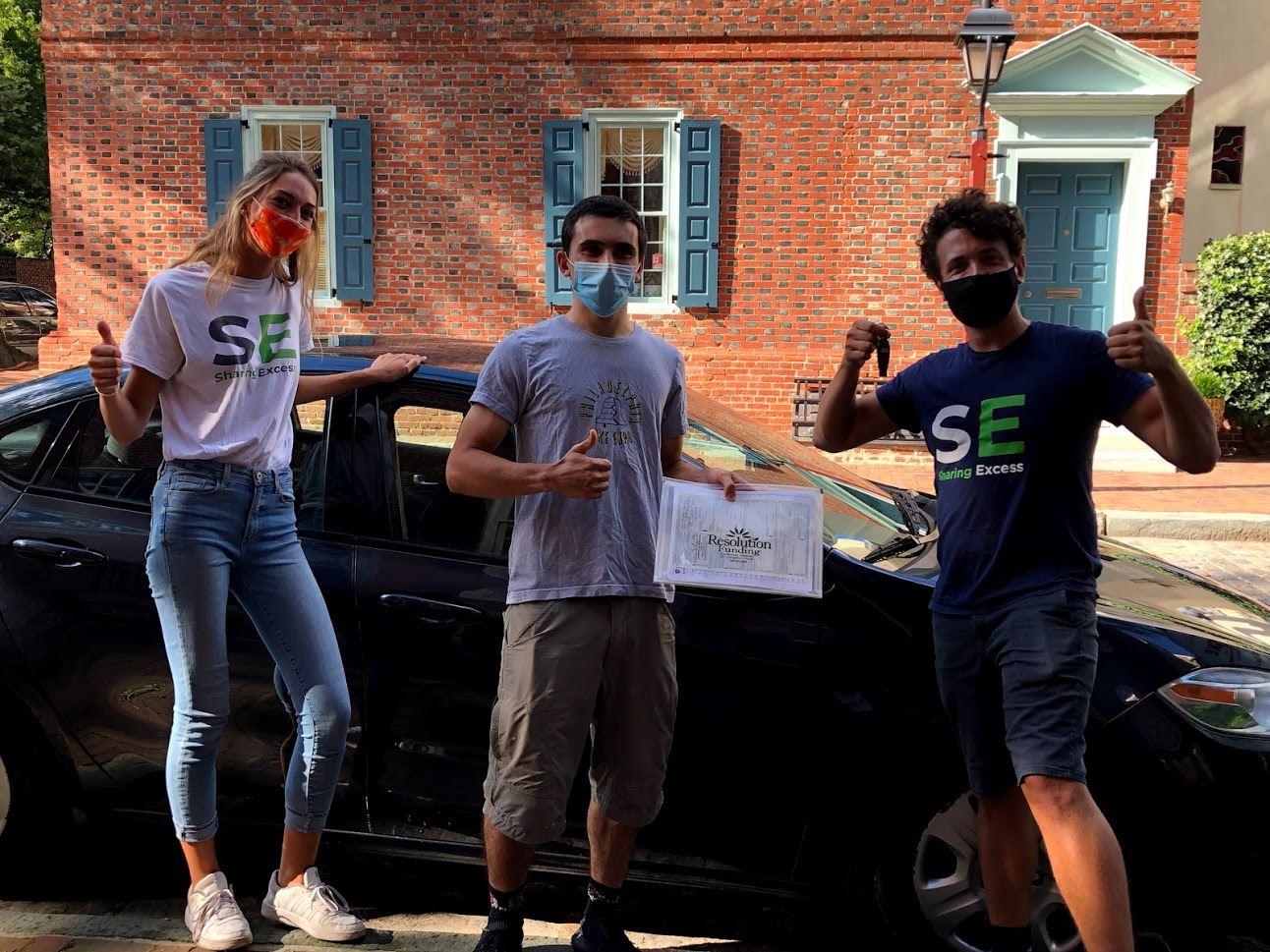 three people standing in front of a car